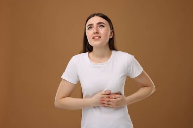 Kahverengi arka planda kalp krizi geçiren kadın.