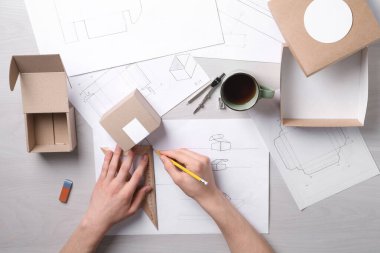 Açık ahşap masa, üst görünümde ambalaj tasarımı oluşturan adam