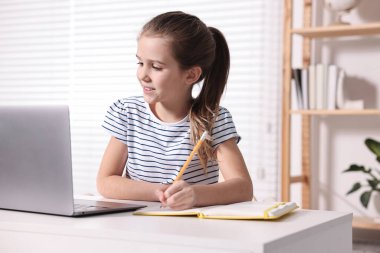 E-öğrenme. İçerideki masada online ders sırasında not alan tatlı kız.