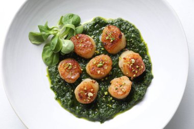 Lezzetli soslu leziz kızarmış deniz tarakları ve beyaz arka planda mısır salatası.