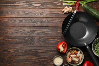 Siyah tava, yemek çubukları ve ahşap masa üzerindeki ürünler. Metin için boşluk