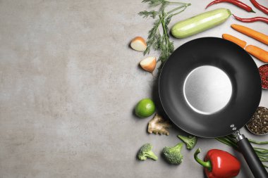 Gri masadaki ham malzemelerle çevrili boş demir tava, düz. Metin için boşluk