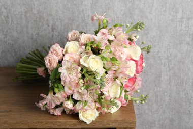 Gri duvarın yakınındaki ahşap masada güzel bir buket taze çiçek.