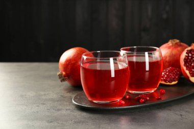 Bardakta lezzetli nar suyu ve gri masada taze meyve. Metin için boşluk