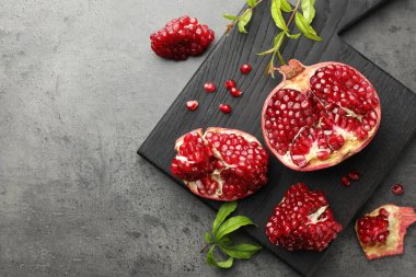 Gri masa üzerinde taze nar ve yeşil yapraklar kes. Metin için boşluk