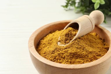 Kavanozda kurutulmuş köri tozu ve hafif ahşap masaya kepçe, yakın plan. Metin için boşluk