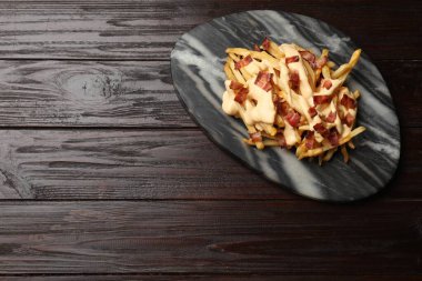 Ahşap masada domuz pastırması ve peynir soslu leziz patates kızartması. Metin için boşluk