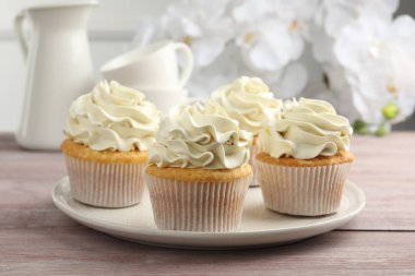 Pembe ahşap masada vanilya kremalı lezzetli kekler, yakın plan.