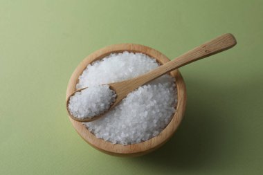 Kâsede organik beyaz tuz ve zeytin zemininde kaşık.