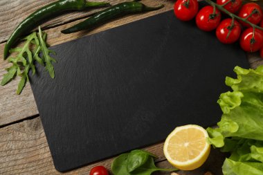 Yemek pişiriyorum. Siyah kesme tahtası ve ahşap masa üzerinde farklı ürünler, düz yatıyordu.