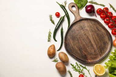 Yemek pişiriyorum. Kesme tahtası ve beyaz ahşap masa üzerindeki farklı ürünler. Metin için boşluk