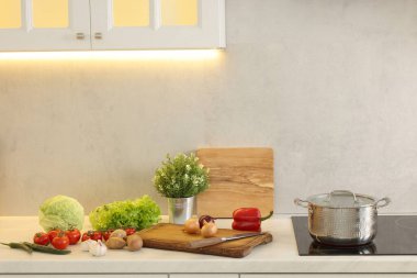 Yemek pişiriyorum. Mutfaktaki tezgahın üstünde taze sebze ve çömlek.