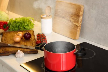 Yemek pişiriyorum. Mutfaktaki tezgahın üstünde taze sebze ve çömlek.