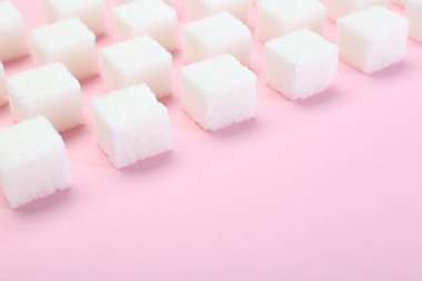 Pembe arka planda beyaz şeker küpleri, yakın plan. Metin için boşluk