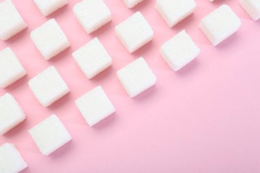 Pembe arka planda beyaz şeker küpleri, üst manzara. Metin için boşluk