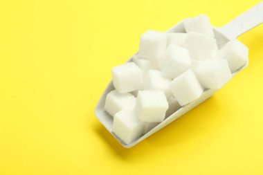 Beyaz şeker küpleri ve sarı arkaplanda kepçe