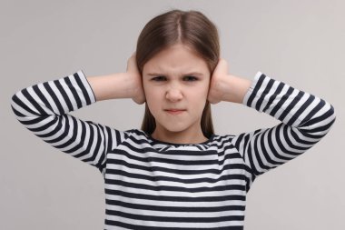 İşitme problemi. Gri arka planda kulak ağrısı çeken küçük bir kız.