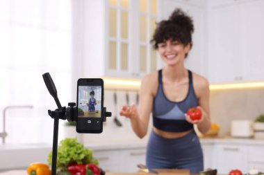 Mutfakta video kaydederken yemek blogcusu yemek pişiriyor, akıllı telefona odaklan