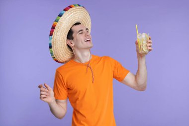 Meksika şapkalı, menekşe arkaplanlı genç adam.