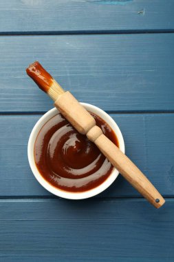 Kasede lezzetli barbekü sosu ve mavi ahşap masada fırça, üst manzara.