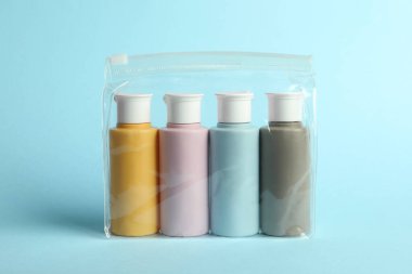 Plastik çantada açık mavi arka planda kozmetik seyahat kiti
