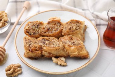 Doğu tatlıları. Lezzetli baklava parçaları, beyaz fayanslı masada ceviz ve çay, yakın plan.