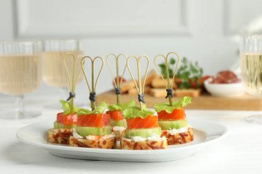 Somon, salatalık, ekmek ve krem peynirli kanepeler beyaz ahşap masada.