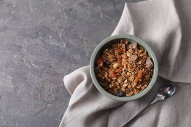 Lezzetli granola kasede, kaşık ve peçete gri desenli masada, düz yerde. Metin için boşluk