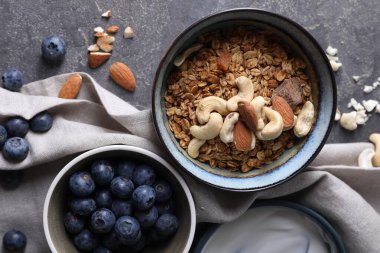 Lezzetli granola, fındıklı fındık ve yaban mersinli gri desenli masa, düz uzanmış.