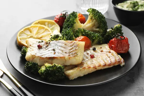Tasty cod cooked with vegetables served on grey table, closeup