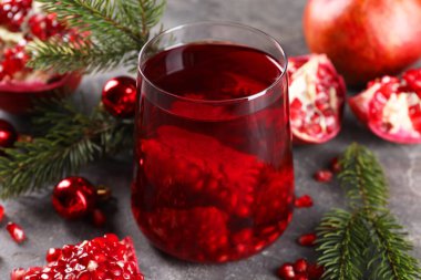 Bardakta Aromatik Sangria içeceği, Noel süsü ve gri masada nar taneleri.