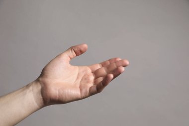 Gri arka planda elinde bir şey tutan adam, yakın plan. Metin için boşluk