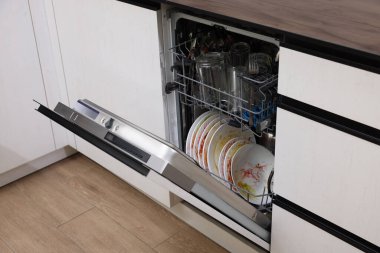 Mutfakta kirli sofra takımı olan modern bulaşık makinesini aç