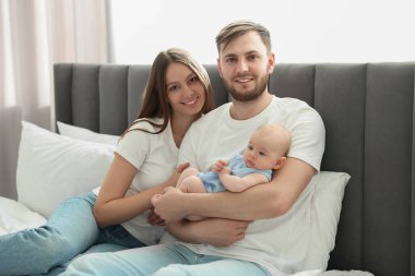 Mutlu bir aile. Anne babalar şirin bebekleriyle evde yatıyorlar.