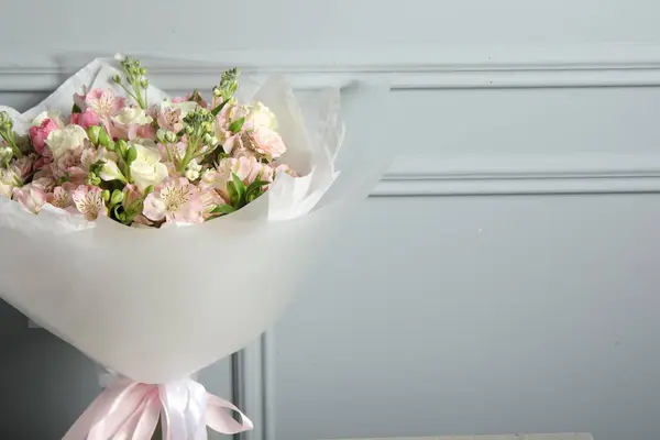 Beautiful bouquet of fresh flowers near grey wall, space for text