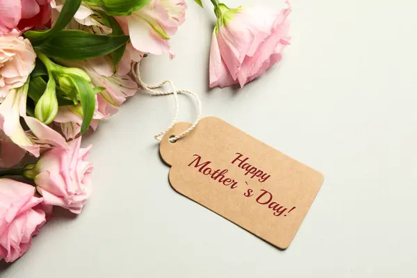 Happy Mother\'s Day greeting label and beautiful flowers on beige background