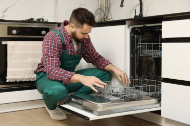 Mutfakta bulaşık makinesini inceleyen bir görevli.