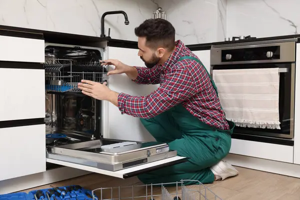 Serviceman repairing dishwasher cutlery rack in kitchen