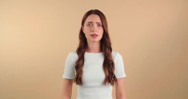  Umut dolu güzel genç bir kadın bej arka planda şans diliyor.