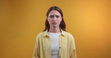  Genç kadın sarı arka planda üzülüyor.