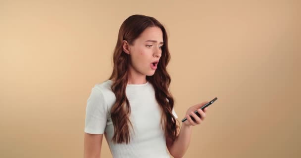 Jovem Desapontada Com Telefone Celular Tem Más Notícias Fundo Bege — Vídeo de Stock