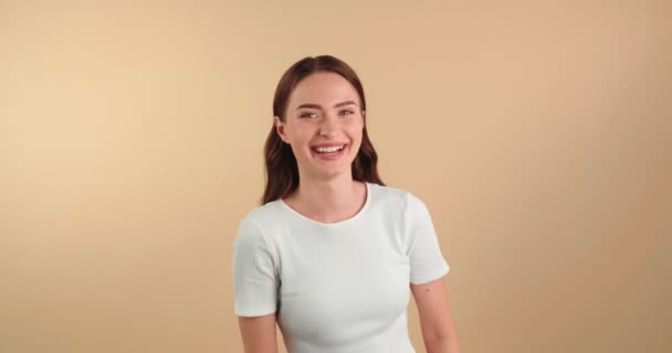 ベージュの背景に笑っている美しい若い女性 — ストック動画