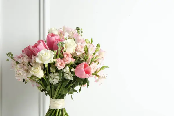 Beautiful bouquet of fresh flowers near white wall. Space for text