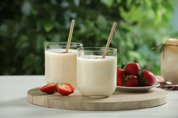 户外白色木制桌子上的玻璃杯和草莓味酸奶 — 图库照片