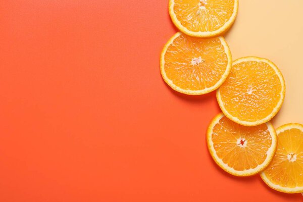 Slices of juicy orange on color background, top view. Space for text