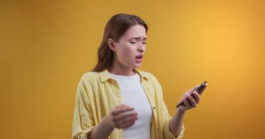  Cep telefonlu hayal kırıklığına uğramış genç bir kadın kötü haberler aldı. Sarı arkaplan