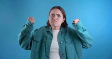  Açık mavi arka planda kızgın genç bir kadın.