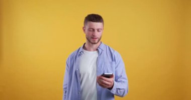  Umutla dolu genç bir adam cep telefonundaki bilgiye üzülüyor. Sarı arkaplan