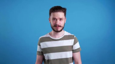  Umutla dolu genç adam açık mavi arka planda seviniyor.