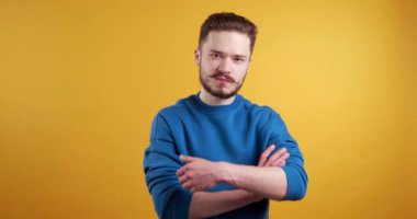  Tehdit. Kızgın genç adam kamerayı işaret ediyor ve sarı arka planda sıkılmış yumruğunu gösteriyor.